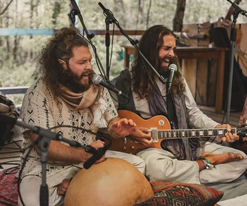 Två av oss sjunger med slutna ögon, en spelar trumma och en gitarr.